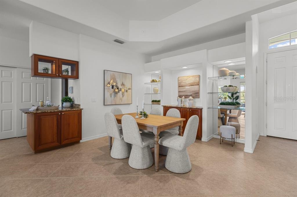 A dining room features a wooden table, upholstered chairs, built-in cabinetry, and tile flooring — 3927 WHISPERING OAKS DRIVE, NORTH PORT, FL