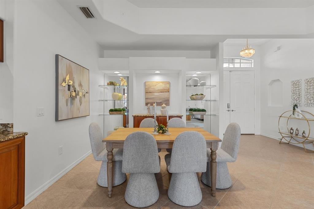 A dining room features a wooden table with six gray chairs and built-in shelving — 3927 WHISPERING OAKS DRIVE, NORTH PORT, FL