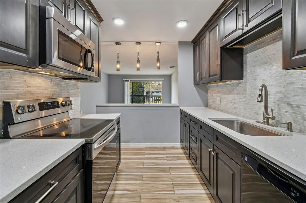 A two-story apartment building exterior features a ground-level patio, a second-story balcony, and lawn — 1695 LEE ROAD UNIT E115, WINTER PARK, FL