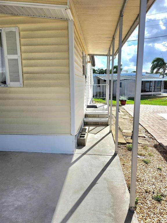 A concrete walkway runs alongside a yellow mobile home with a covered porch area — 6509 OREGON STREET, BRADENTON, FL