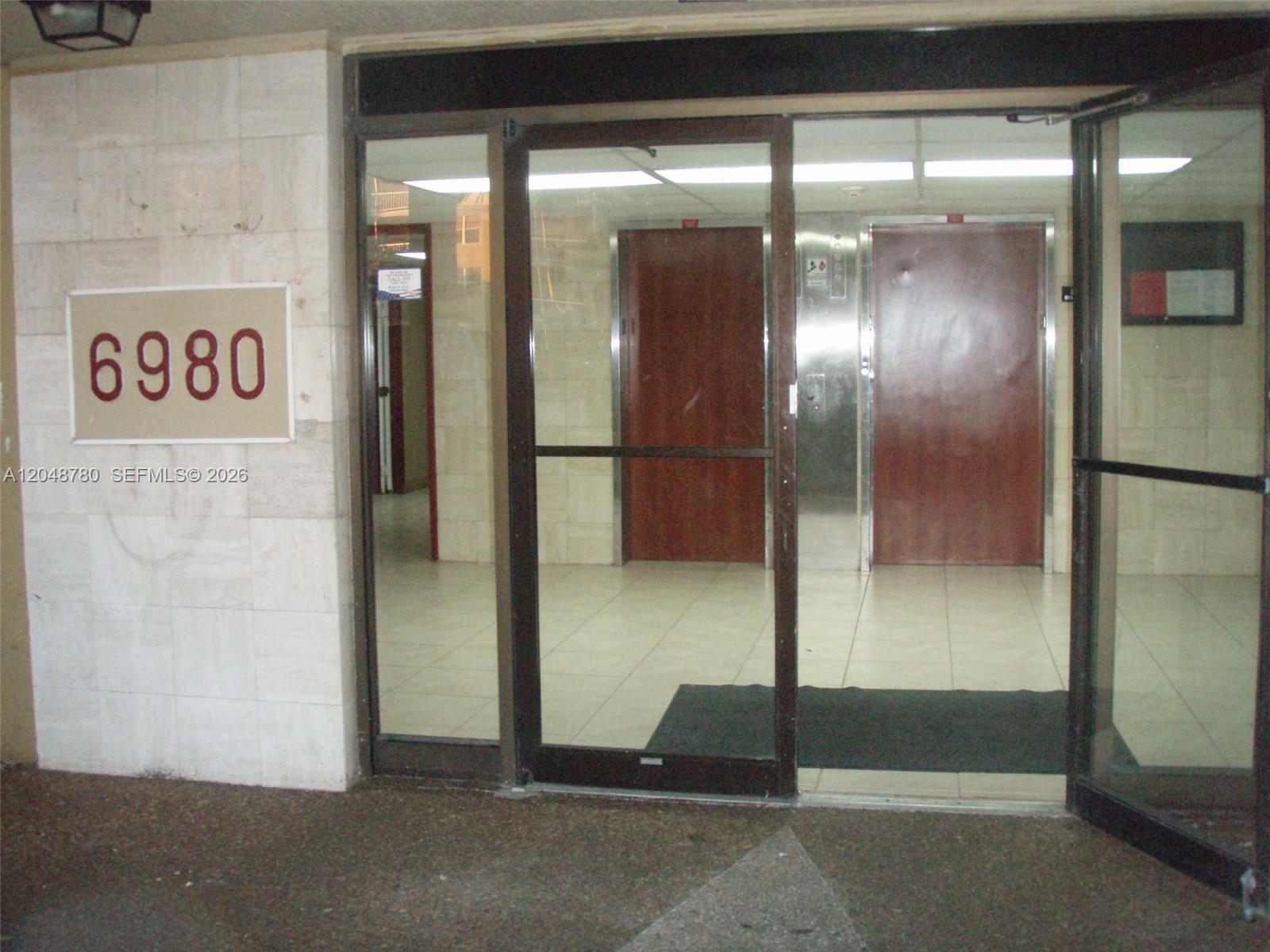 A glass entrance door leads to a lobby with two elevators and tiled floors — 6980 NW 186th St # 522, Hialeah FL 33015, HIALEAH, FL