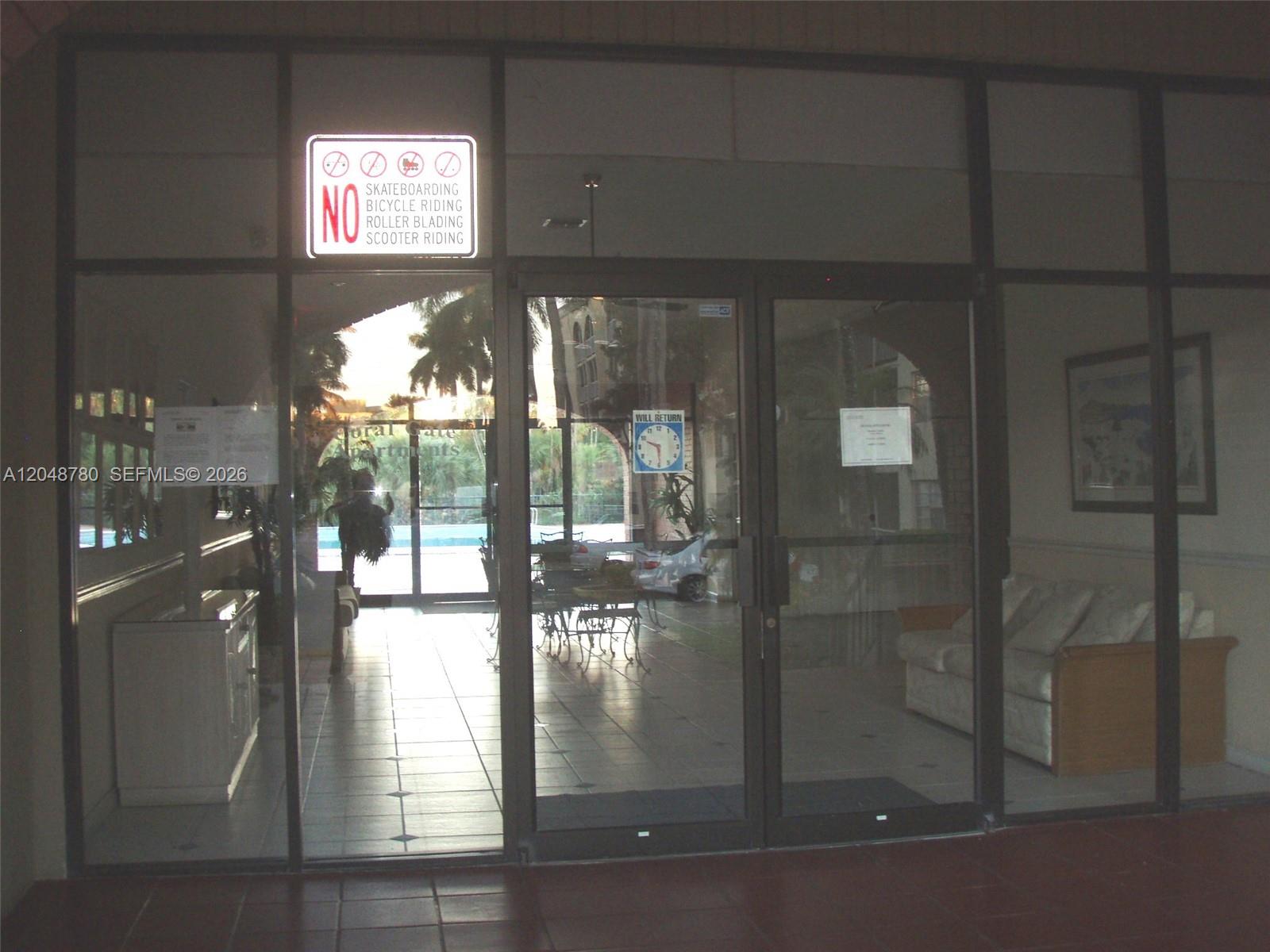 A glass-paneled entrance door leads into a lobby with tile flooring and a sofa — 6980 NW 186th St # 522, Hialeah FL 33015, HIALEAH, FL
