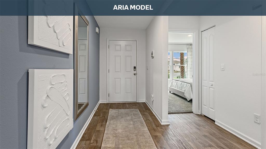 A hallway with wood-look flooring, a blue accent wall, a mirror, and a white door — 68 SAWDUST LANE, PALM COAST, FL