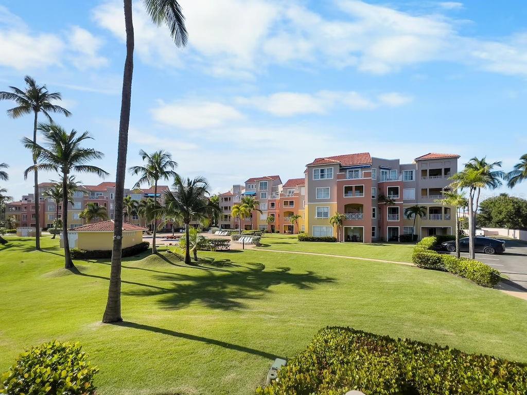 A multi-story apartment complex with palm trees and a grassy lawn under a blue sky — 170 Candelero Dr. PALMAS DEL MAR, LAS PALMAS DORADAS UNIT 501, HUMACAO, PR