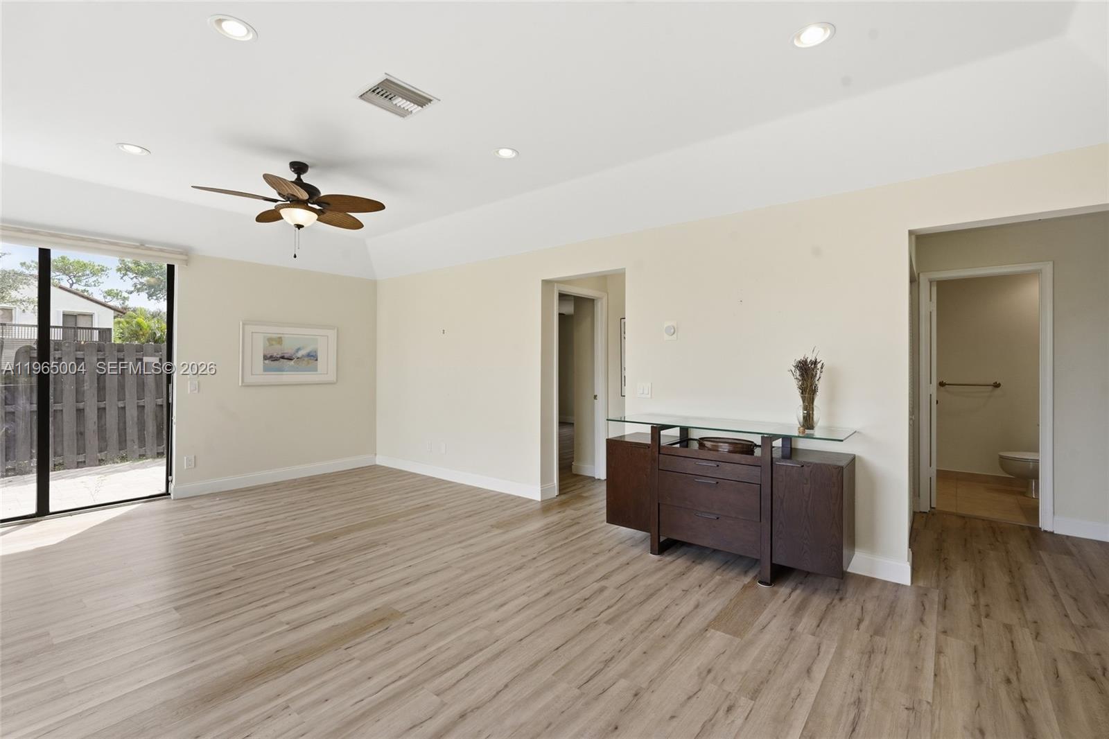 A spacious room features light wood-look flooring, a ceiling fan, and a glass-topped console table — 5726 Fox Hollow Dr # A, Boca Raton FL 33486, BOCA RATON, FL