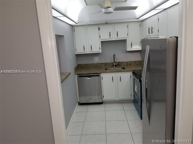 A kitchen features white cabinets, granite countertops, stainless steel appliances, and light-colored tile flooring — 4160 Inverrary Dr # 505, Lauderhill FL 33319, LAUDERHILL, FL