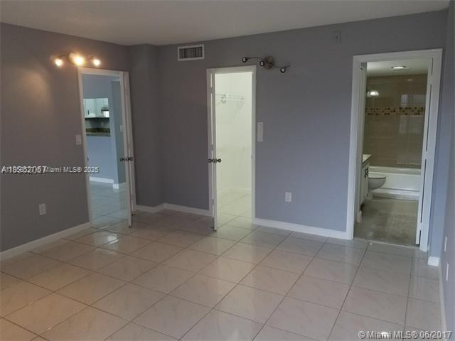 A room with light-colored tile flooring, gray walls, and three open doorways leading to other spaces — 4160 Inverrary Dr # 505, Lauderhill FL 33319, LAUDERHILL, FL