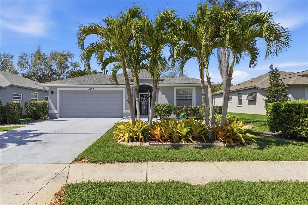 A single-story house with a gray garage, palm trees, and a landscaped front yard — 6726 W COUNTRY CLUB LANE, SARASOTA, FL
