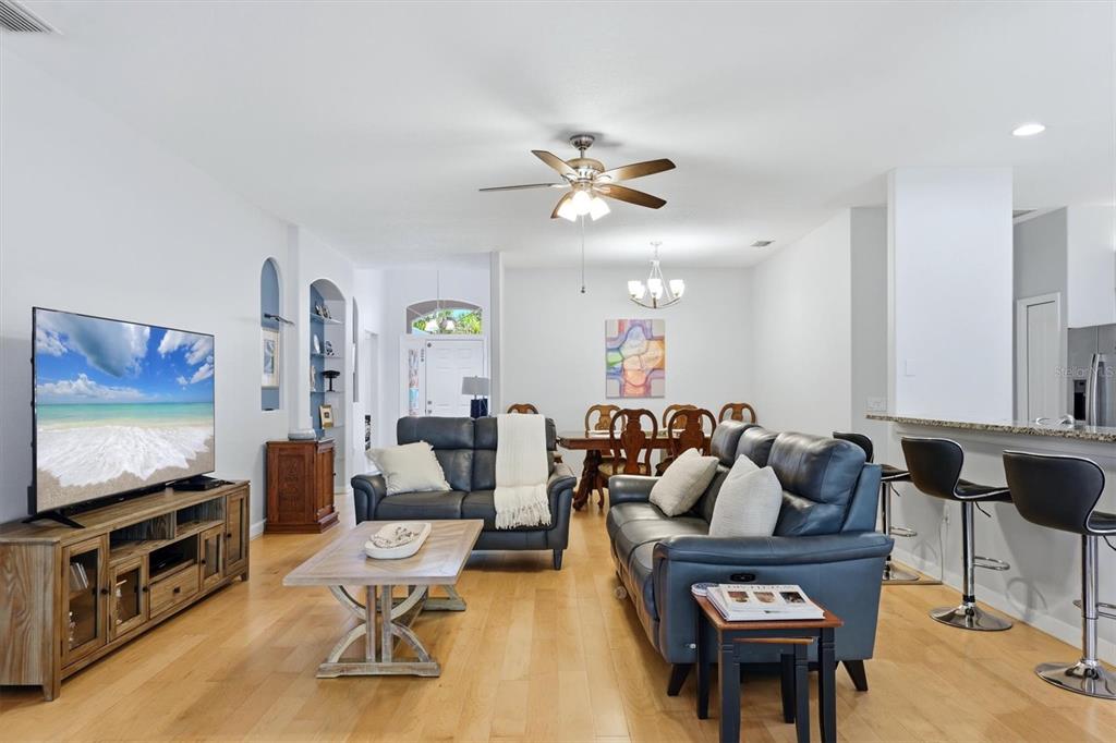 A living room with light wood floors, two leather sofas, and a dining area beyond — 6726 W COUNTRY CLUB LANE, SARASOTA, FL