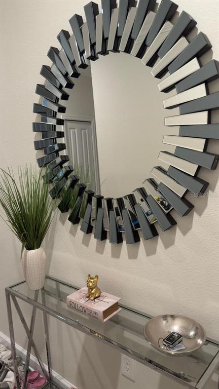 A glass console table sits below a large, decorative sunburst mirror on a beige wall — 2787 PUNCTUATION PLACE, KISSIMMEE, FL