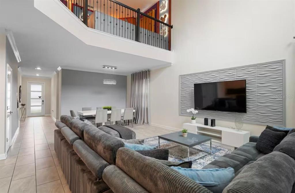 A living room with a high ceiling, a wall-mounted television, and an adjacent dining area — 2787 PUNCTUATION PLACE, KISSIMMEE, FL