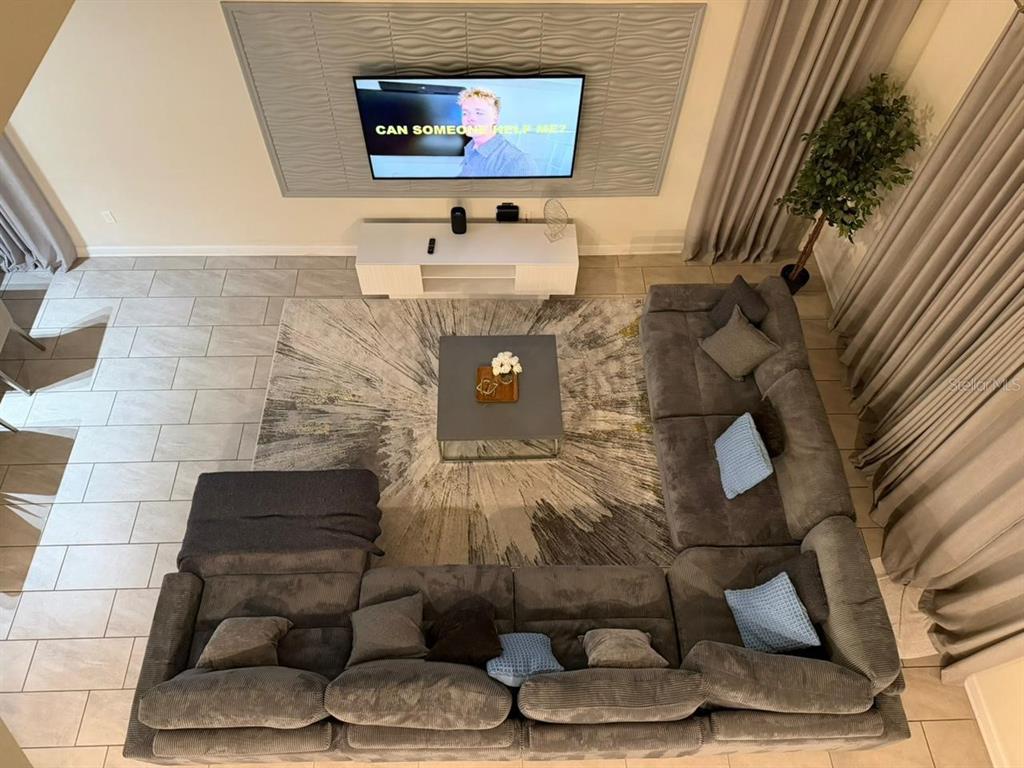 A high-angle view of a living room featuring a large sectional sofa, area rug, and television — 2787 PUNCTUATION PLACE, KISSIMMEE, FL