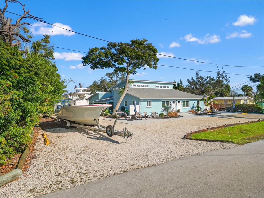 A light blue house with a boat on a trailer parked in a gravel driveway — 3155 WATERSIDE DRIVE, ENGLEWOOD, FL