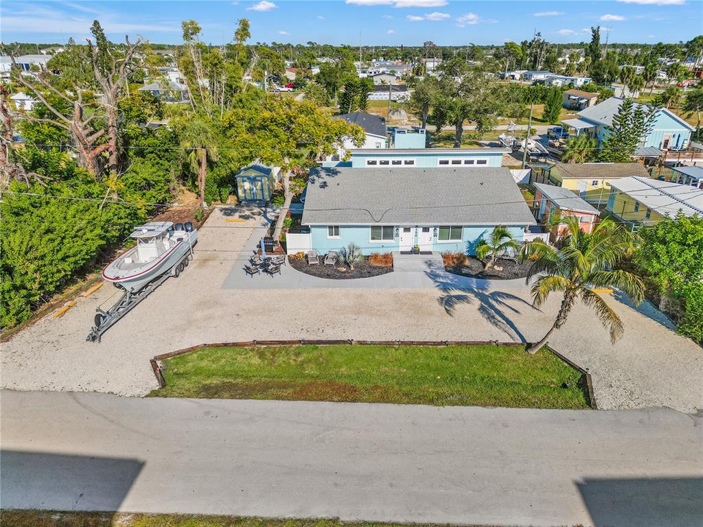 An aerial view shows a light blue house with a gray roof, gravel yard, and boat — 3155 WATERSIDE DRIVE, ENGLEWOOD, FL
