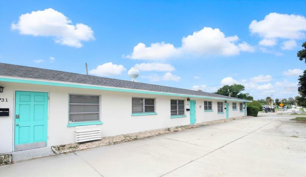 A single-story white apartment building with turquoise doors and a concrete parking area — 6383 GATEWAY AVENUE UNIT 6383, SARASOTA, FL