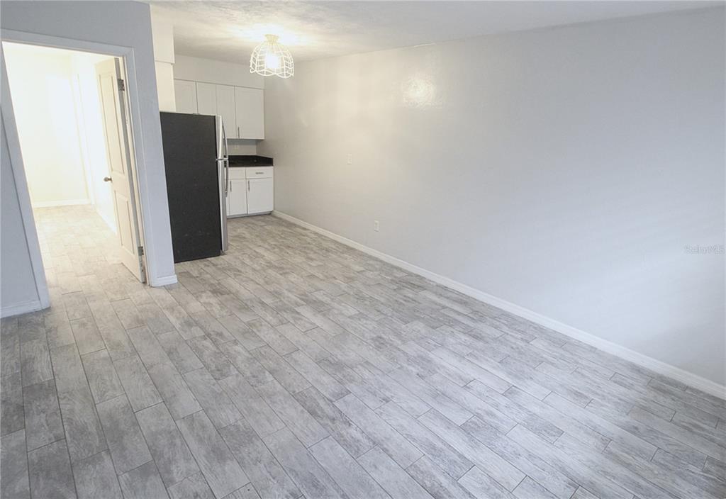 A kitchen area with white cabinets, a black refrigerator, and gray wood-look tile flooring — 6383 GATEWAY AVENUE UNIT 6383, SARASOTA, FL