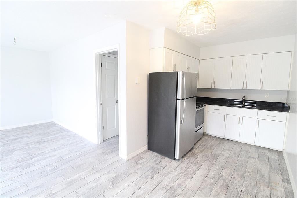 A kitchen with white cabinets, black countertops, and stainless steel appliances over wood-look tile flooring — 6383 GATEWAY AVENUE UNIT 6383, SARASOTA, FL