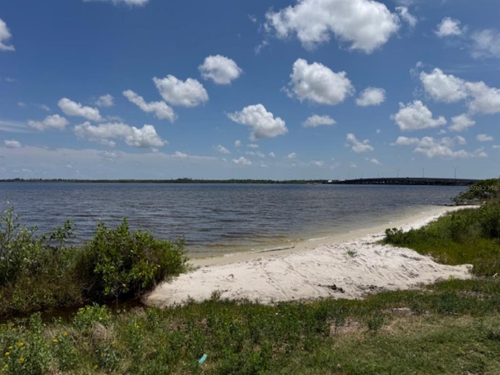 A sandy beach borders a large body of water under a bright, cloudy blue sky — 14484 ARMADA ROAD, PORT CHARLOTTE, FL