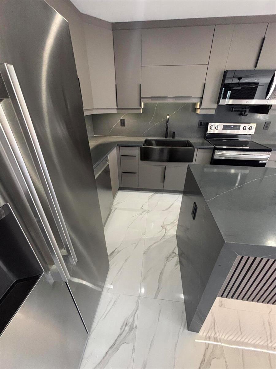 A modern kitchen features gray cabinets, dark countertops, a farmhouse sink, and white marble flooring — 4695 Sable Pine Circle # C2, West Palm Beach FL 33417, WEST PALM BEACH, FL