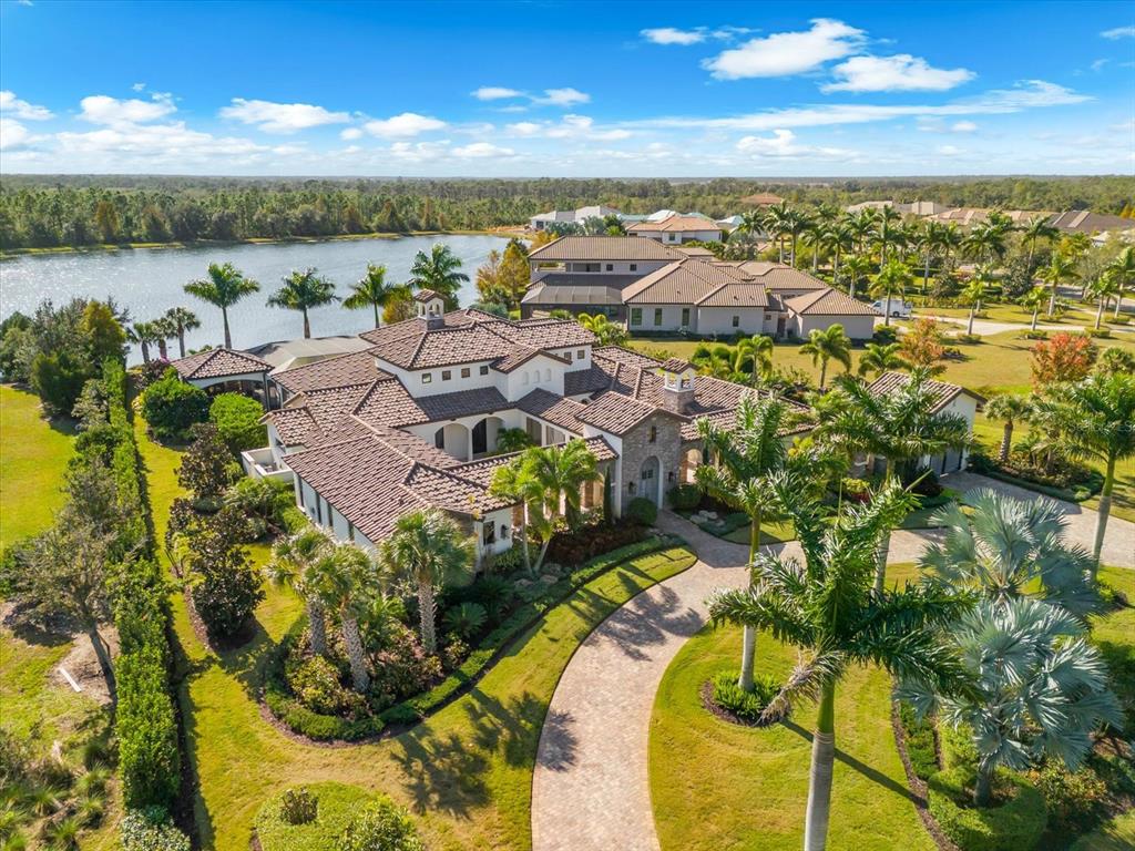 An aerial view of a large Mediterranean-style house with a tile roof and circular driveway — 20906 PARKSTONE TERRACE, LAKEWOOD RANCH, FL