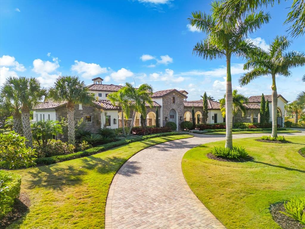 A large Mediterranean-style house with a stone facade and a curved brick driveway — 20906 PARKSTONE TERRACE, LAKEWOOD RANCH, FL