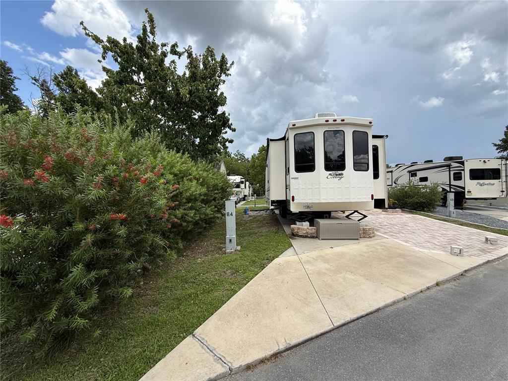 A white recreational vehicle is parked on a paved lot next to a green hedge — 2856 NE 104TH AVENUE, SILVER SPRINGS, FL