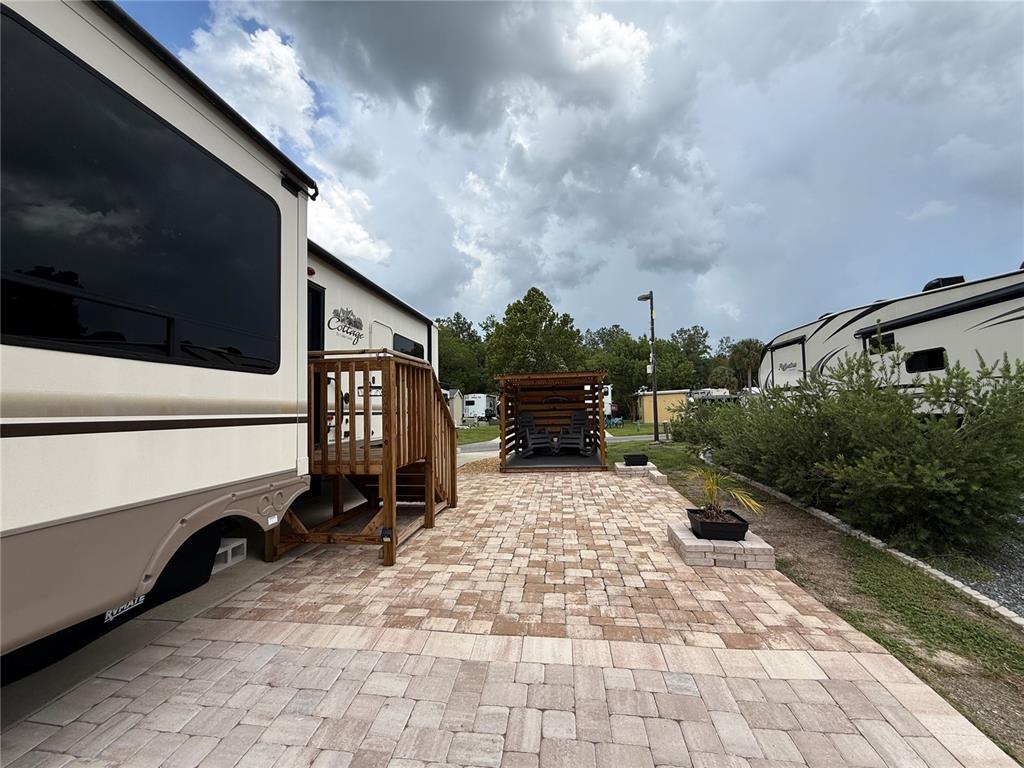 A paved patio sits between two recreational vehicles with a wooden deck and covered seating area — 2856 NE 104TH AVENUE, SILVER SPRINGS, FL