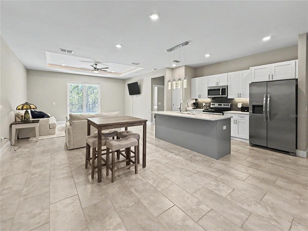 An open-concept kitchen and living area features a gray island, white cabinets, and tile flooring — 4667 BRASHER AVENUE, NORTH PORT, FL