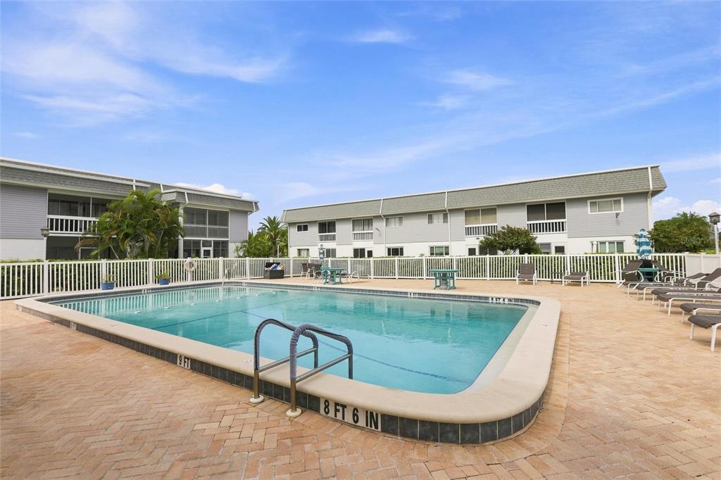 A rectangular swimming pool is surrounded by a brick patio and two-story apartment buildings — 22375 EDGEWATER DRIVE UNIT 204, PORT CHARLOTTE, FL