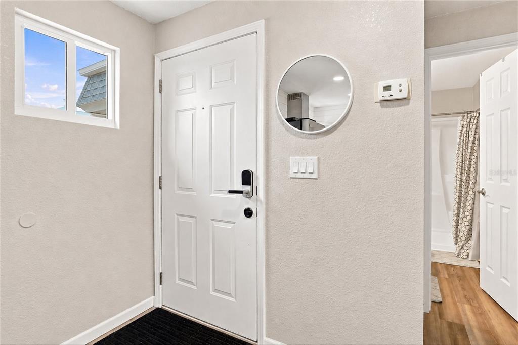 An entryway features a white front door, a small window, and a circular wall mirror — 22375 EDGEWATER DRIVE UNIT 204, PORT CHARLOTTE, FL