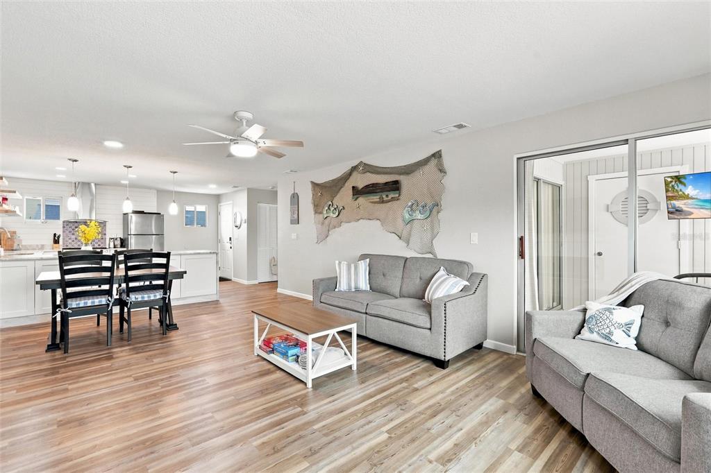 A living room and kitchen area feature gray sofas, wood-look flooring, and a fishing net decoration — 22375 EDGEWATER DRIVE UNIT 204, PORT CHARLOTTE, FL