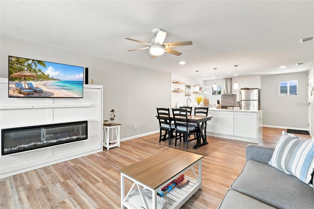 An open-concept living and dining area features wood-look flooring, a fireplace, and a kitchen island — 22375 EDGEWATER DRIVE UNIT 204, PORT CHARLOTTE, FL