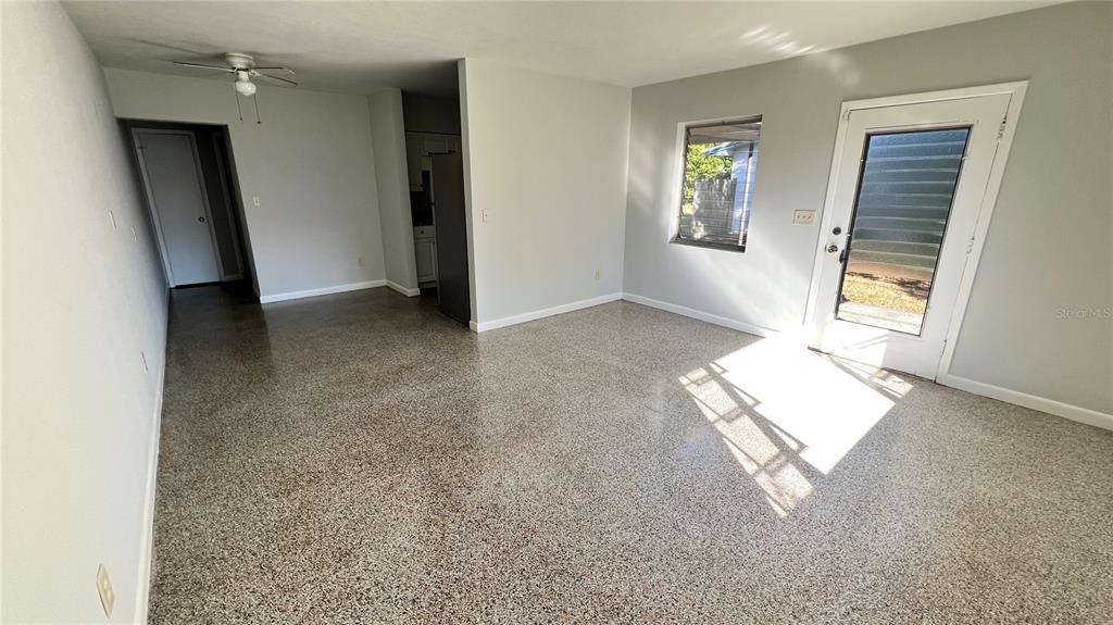 An empty room features light gray walls, a speckled epoxy floor, and a glass-paneled door — 2323 BELMAR DRIVE, BELLEAIR BLUFFS, FL