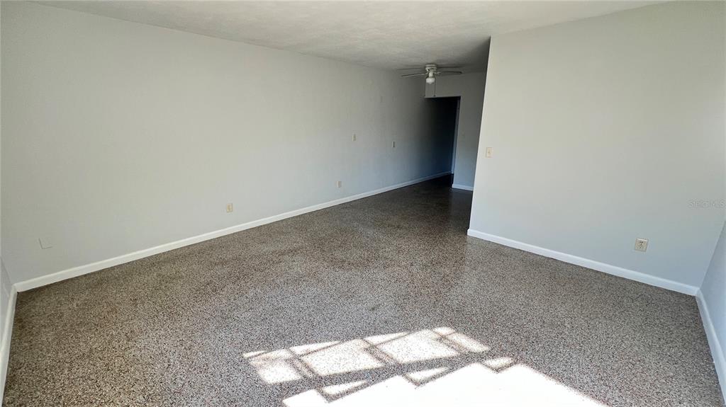 An empty room with light gray walls and speckled flooring features a ceiling fan — 2323 BELMAR DRIVE, BELLEAIR BLUFFS, FL