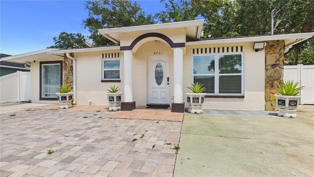 A single-story house with a paved driveway, stone accents, and a covered front entryway — 8721 N ORANGEVIEW AVENUE, TAMPA, FL