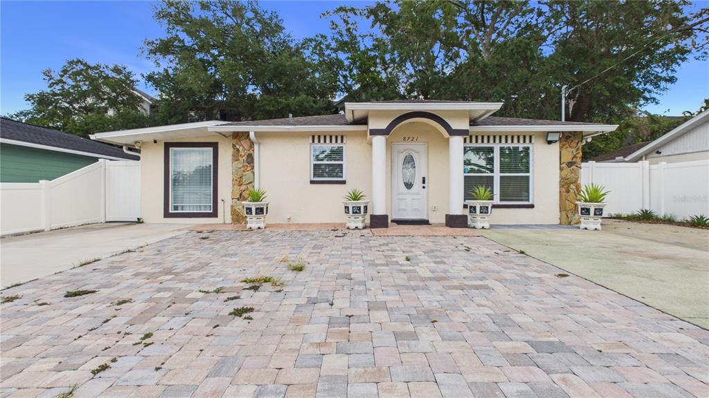 A single-story house with a paved driveway, stone accents, and a central covered entryway — 8721 N ORANGEVIEW AVENUE, TAMPA, FL