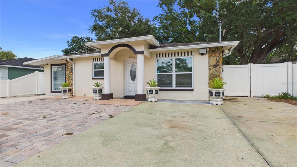 A single-story house features a stucco exterior, a covered entryway with columns, and a driveway — 8721 N ORANGEVIEW AVENUE, TAMPA, FL