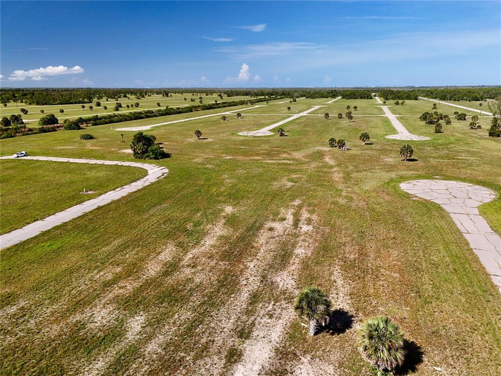 An aerial view shows a large, undeveloped grassy lot with paved roads and scattered trees — 12392 BONITA PLACE, PLACIDA, FL