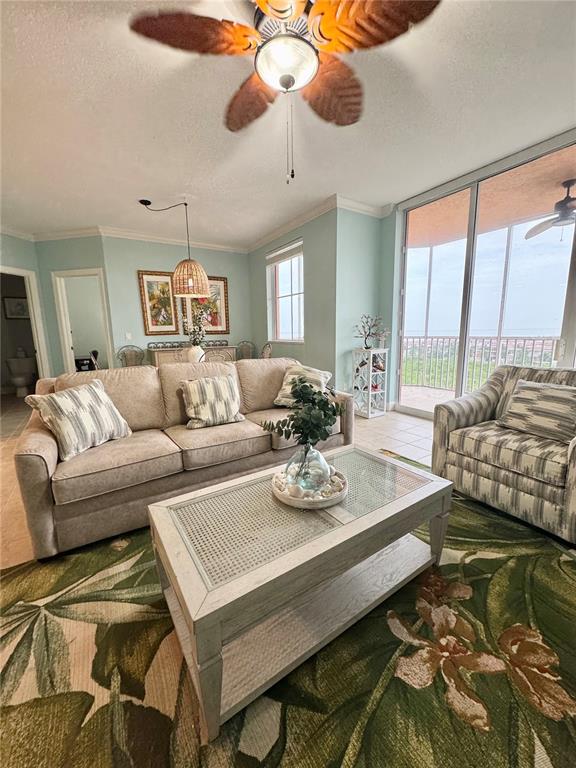 A living room with a beige sofa, patterned armchair, coffee table, and a balcony view — 3191 MATECUMBE KEY ROAD UNIT 607, PUNTA GORDA, FL