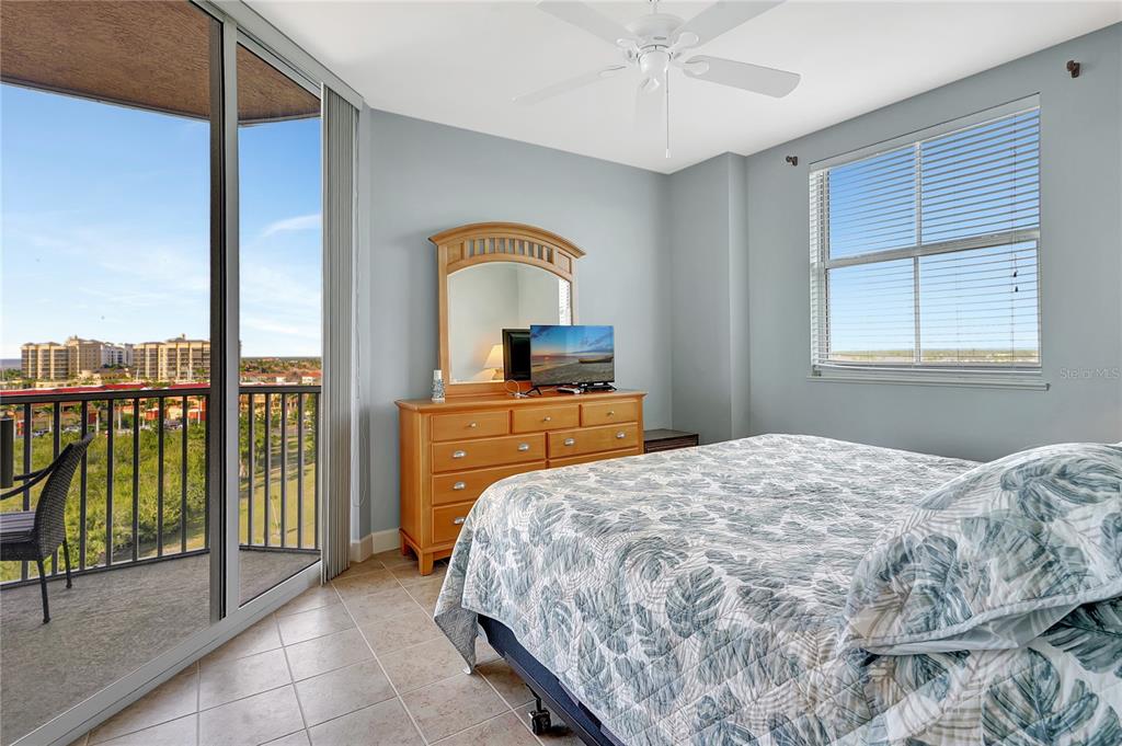 A bedroom with tile floors, a wooden dresser, a ceiling fan, and a balcony view — 3191 MATECUMBE KEY ROAD UNIT 607, PUNTA GORDA, FL