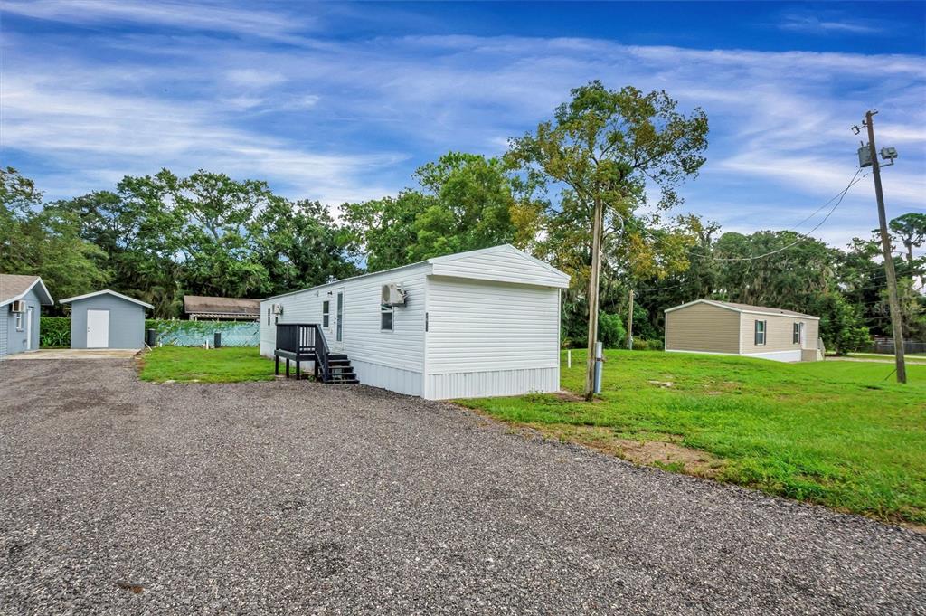A white mobile home sits on a gravel lot with a small deck and shed — 2667 SNAPPING TURTLE DRIVE, LAKE WALES, FL