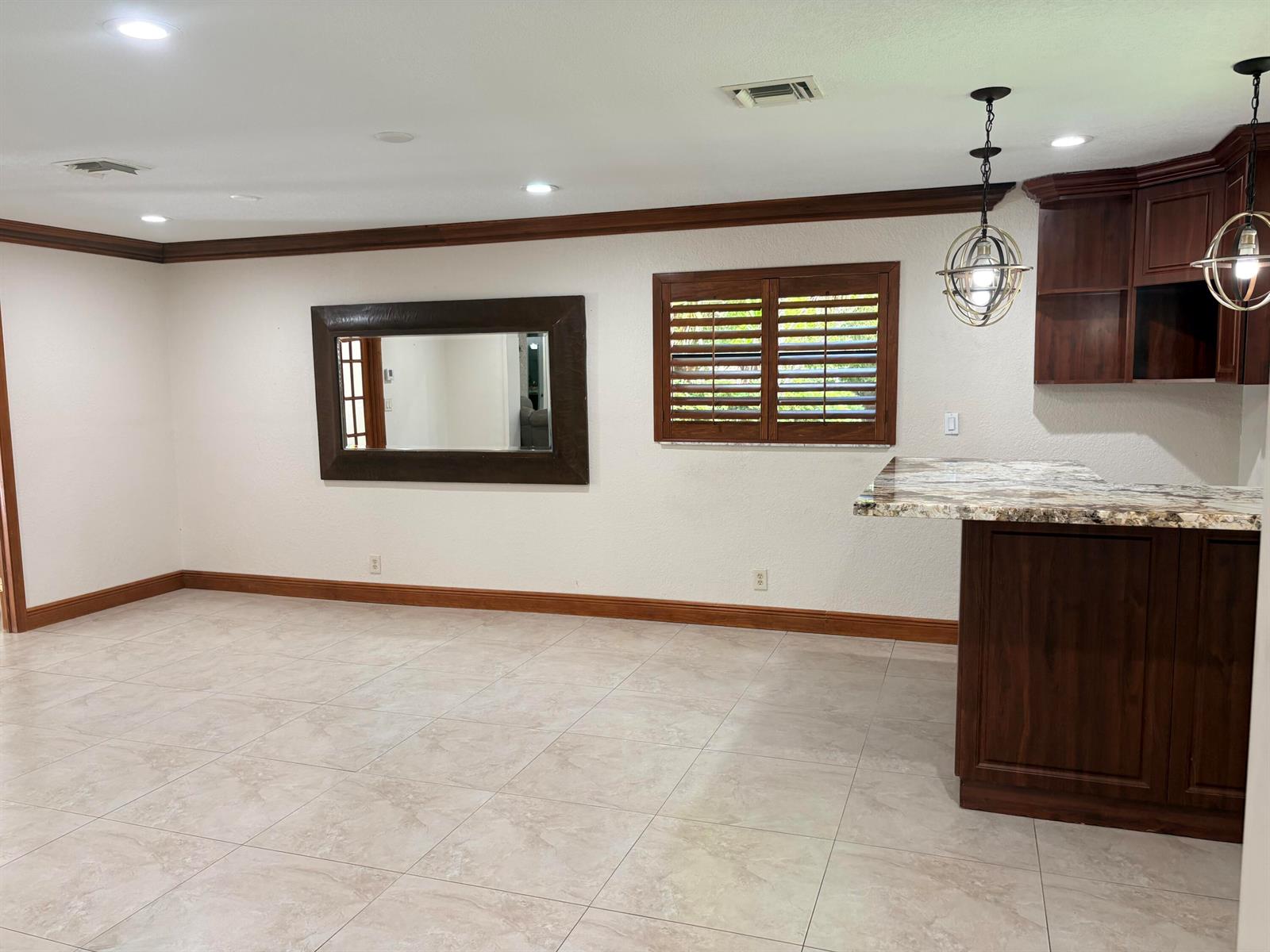 A room with tile floors, a large wall mirror, wooden shutters, and a granite-topped bar — 15943 W Wind Circle, Sunrise FL 33326, SUNRISE, FL