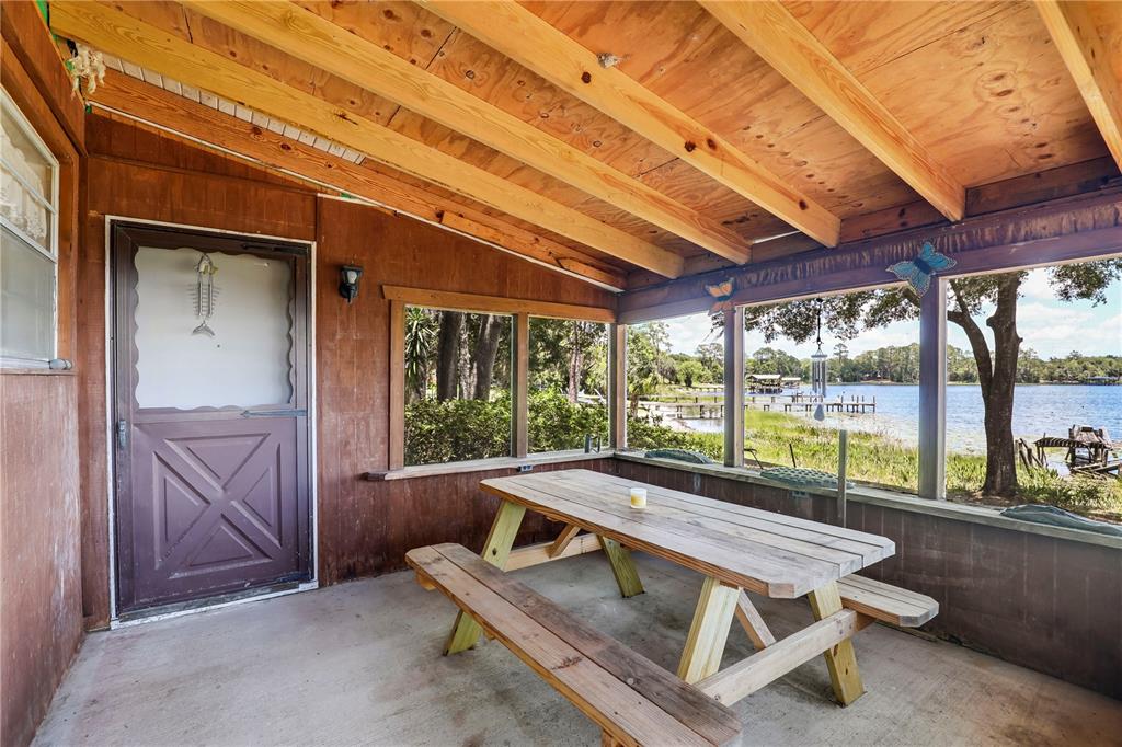 A covered wooden porch features a picnic table, concrete floor, and views of a lake — 104 CARTER WHITTAKER LANE, POMONA PARK, FL