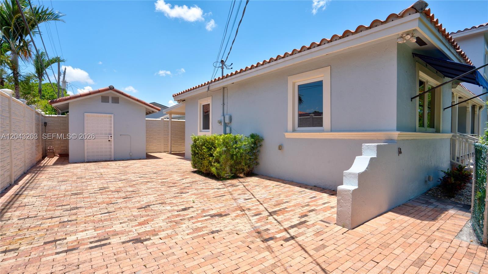 A light blue house with a brick patio and a detached shed under a blue sky — 500 SW 51st Ct # 1, Miami FL 33134, MIAMI, FL
