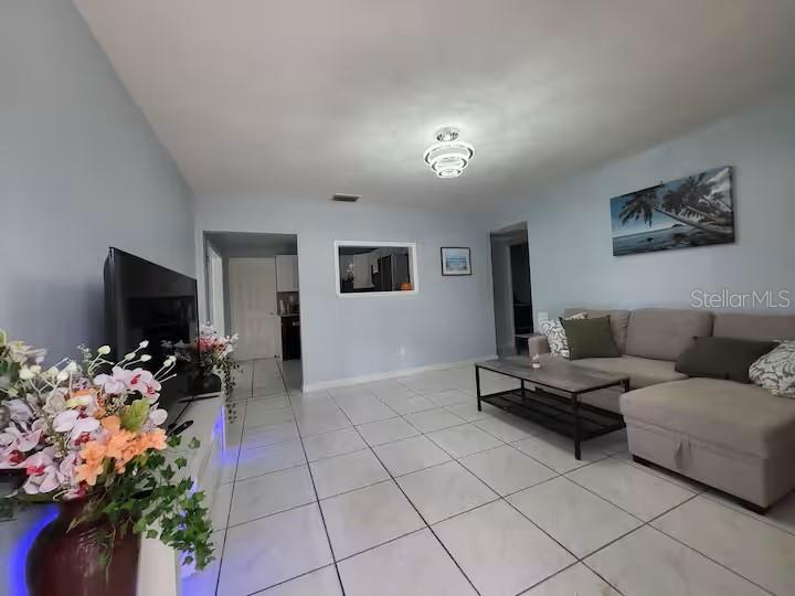 A living room features light blue walls, white tile flooring, and a sectional sofa — 3552 38TH AVENUE N, ST PETERSBURG, FL