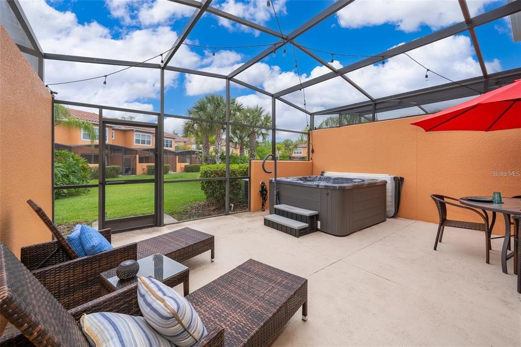 A screened-in patio features a hot tub, outdoor furniture, and a view of the lawn — 2665 TRIUMPH WAY, KISSIMMEE, FL