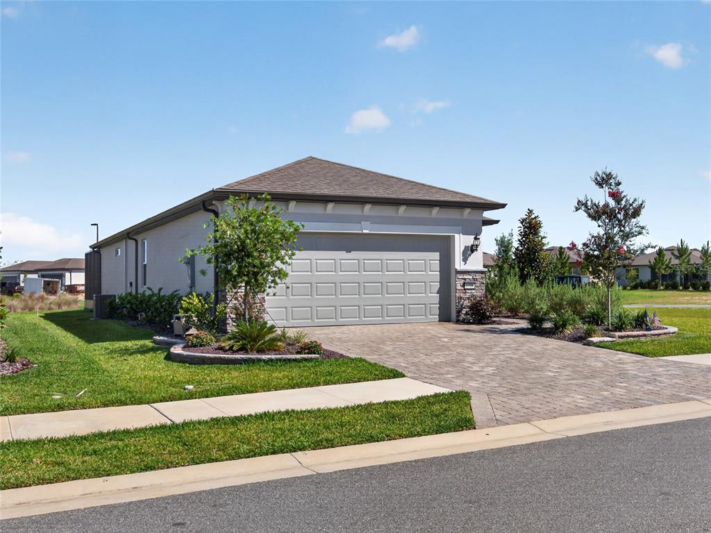 A single-story house with a gray garage door, paver driveway, and landscaped front yard — 5798 SW 86TH AVENUE ROAD, OCALA, FL