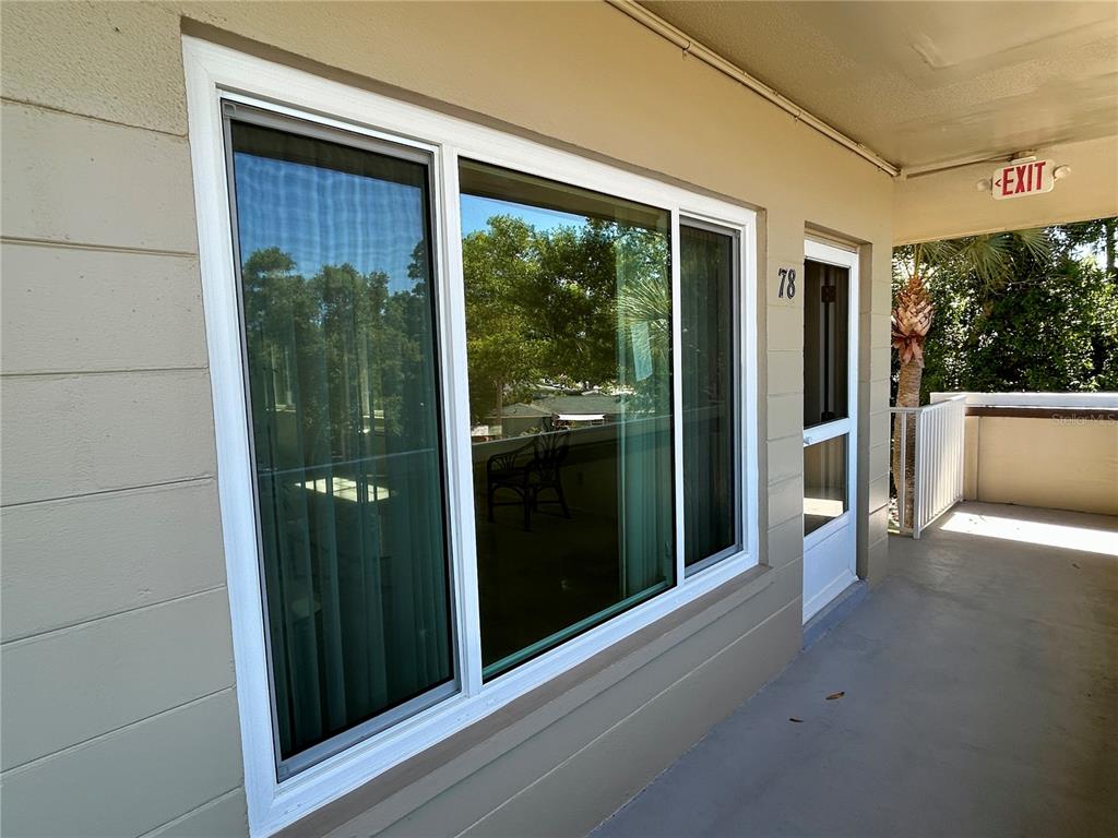 A view of a building exterior featuring a large window and a door labeled 78 — 2464 AUSTRALIA WAY E UNIT 78, CLEARWATER, FL