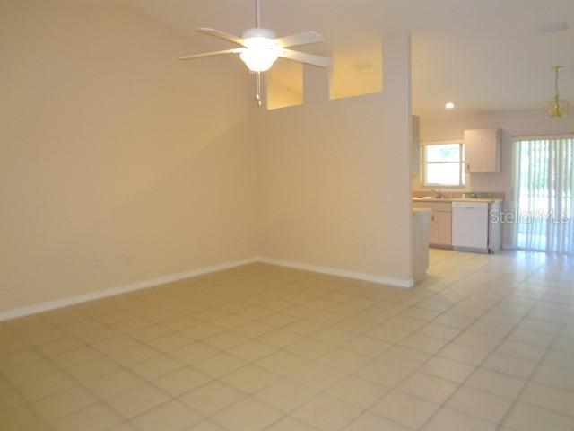 An open-concept living area with tile flooring, a ceiling fan, and an adjacent kitchen — 11 PONTIAC LANE UNIT B, PALM COAST, FL