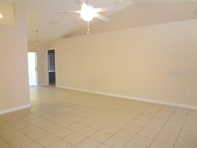 A spacious living room features light-colored tile flooring, a vaulted ceiling, and a ceiling fan — 11 PONTIAC LANE UNIT B, PALM COAST, FL